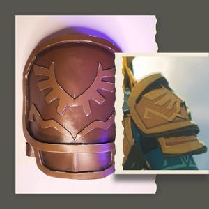 May include: A brown shoulder armour piece with a stylized sunburst design. The armour has a metallic finish and is likely part of a costume or cosplay. The design is reminiscent of a video game.