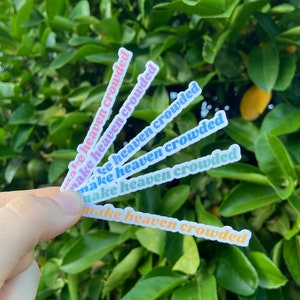 May include: A set of six colorful stickers with the text "Make heaven crowded" in a retro font. The stickers are arranged in a fan shape and are held in a hand.