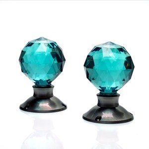 May include: Two teal blue crystal door knobs with a faceted design and a silver base.