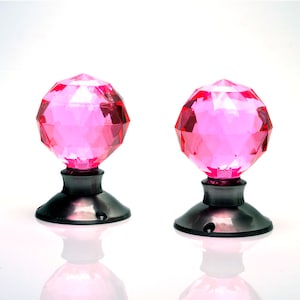 May include: Two pink crystal door knobs with a faceted design and a silver base.