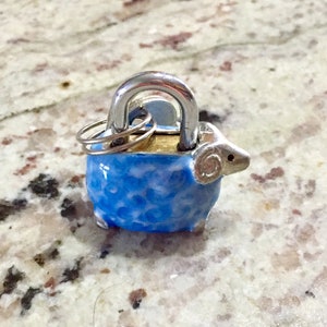 May include: A blue and white sheep-shaped padlock with a silver keyhole and two silver keys attached.