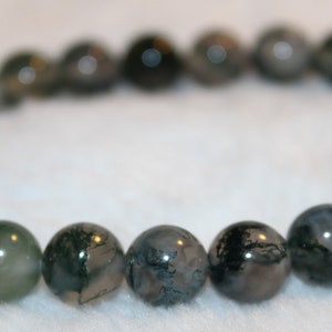 Peut inclure: Un bracelet de perles rondes en agate mousse polie. Les perles présentent des motifs verts, gris et blancs. Le bracelet est monté sur un cordon élastique, un accessoire en pierre naturelle.