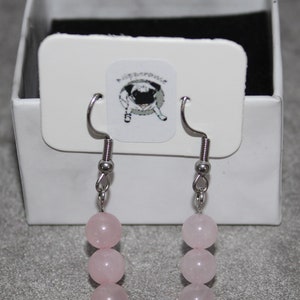 May include: A pair of silver earrings with three pink rose quartz beads on each earring.