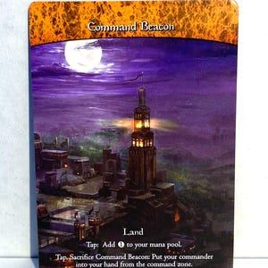 May include: A rectangular card featuring a nighttime cityscape with a tall, illuminated tower under a full moon. The card is labeled "Command Beacon" and includes game instructions. The top border has an orange, textured design.