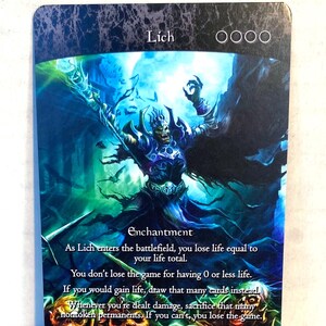 Może przedstawiać: Karta fantasy z napisem "Lich" u góry. Karta przedstawia niebiesko-fioletową postać nieumarłego z wyciągniętymi ramionami, na niebiesko-zielonym tle. Tekst szczegółowo opisuje zasady zaklęcia karty.
