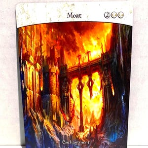 May include: A rectangular card with the word "Moat" at the top. The card features a fantasy illustration of a burning castle with a bridge. The text "Enchantment" and "Creatures without flying can't attack" are at the bottom.