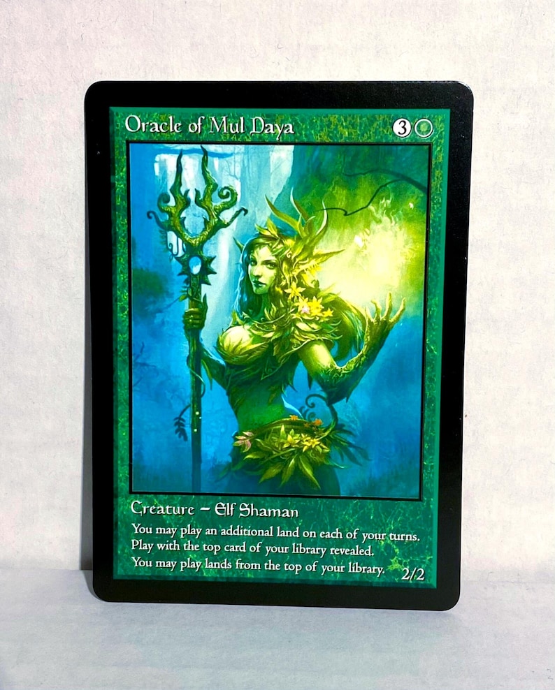 May include: A Magic: The Gathering card featuring the "Oracle of Mul Daya." The card has a green background with an illustration of a female elf shaman holding a staff. Text includes the card's name, mana cost, creature type, and abilities.
