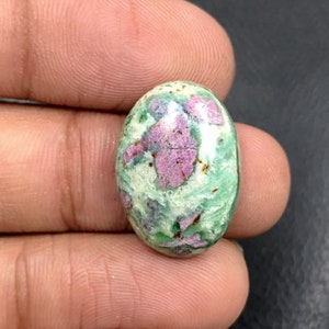 Puede incluir: Piedra preciosa ovalada en cabujón con un patrón verde y rosa. La piedra tiene un aspecto jaspeado con remolinos de verde y blanco, e inclusiones rosas.