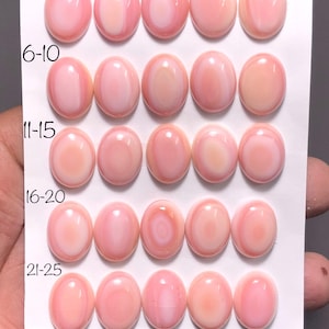 Puede incluir: Veinticinco gemas ovaladas pulidas, en tonos rosados y blancos, dispuestas sobre una tarjeta blanca. Las gemas miden aproximadamente 12 mm x 16 mm. La tarjeta está numerada del 1 al 25, indicando la posición de cada gema.