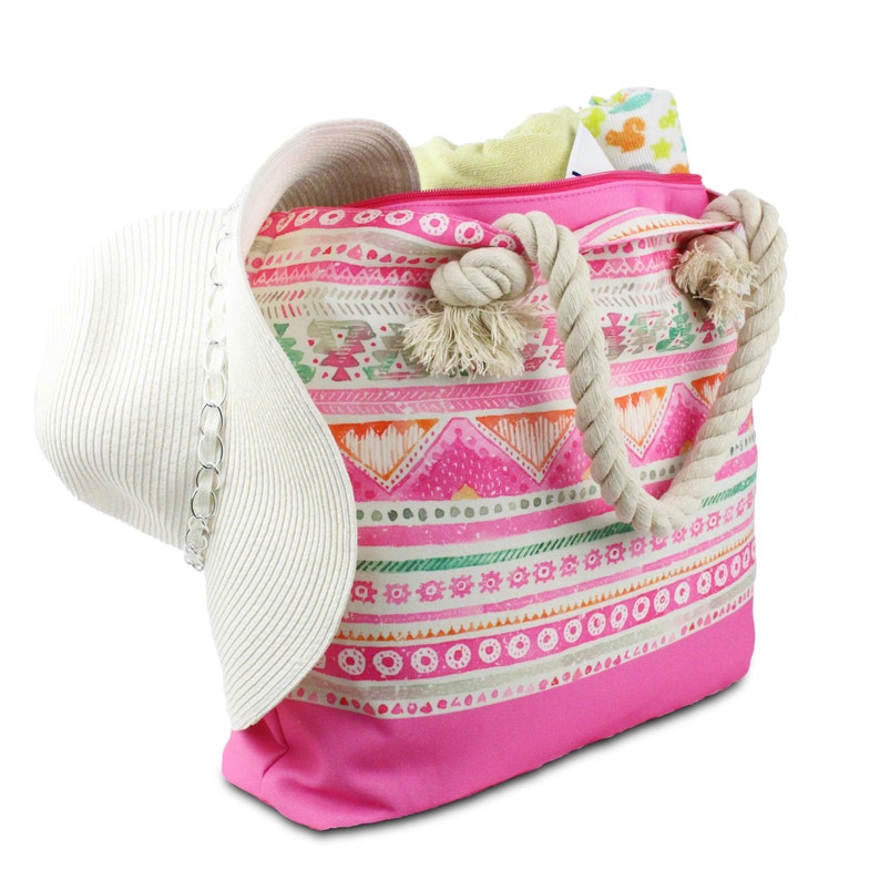May include: A pink and white beach tote bag with a rope handle and a geometric pattern. The bag is filled with a white hat and a towel.