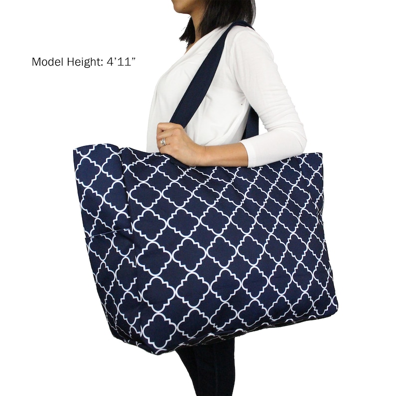 May include: A large navy blue tote bag with a white geometric pattern. The bag has two long straps and a spacious interior. Model Height: 4'11"