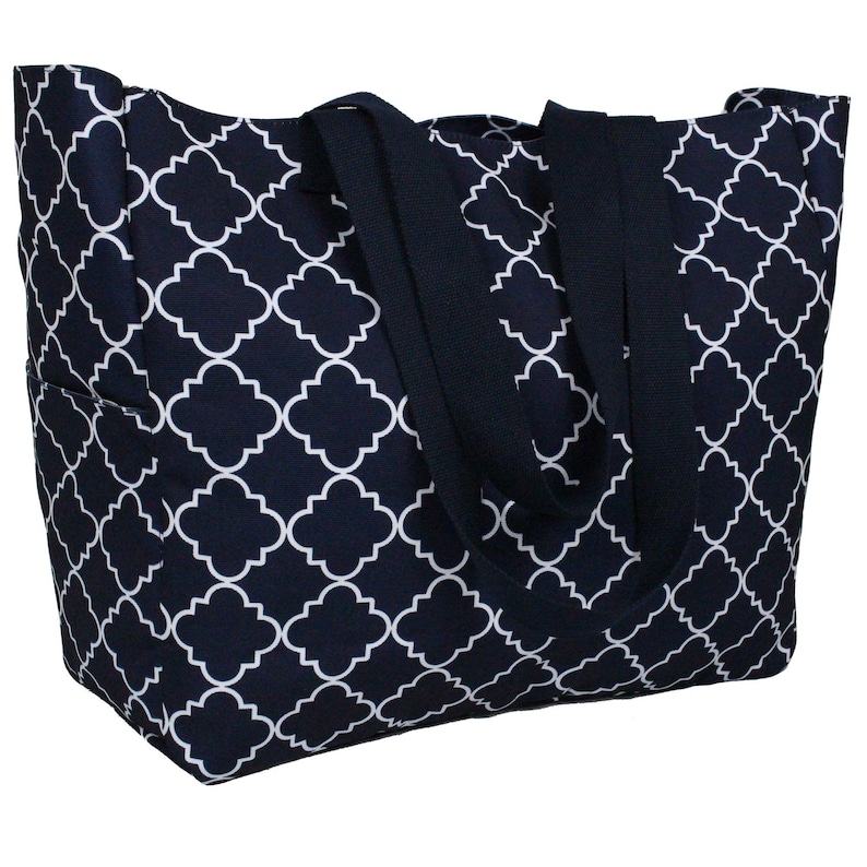 May include: A large navy blue tote bag with white geometric pattern. The bag has two wide black straps.