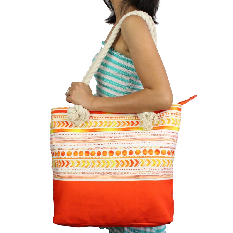 May include: A large orange and white tote bag with a geometric pattern. The bag has a white rope handle and a zipper closure.