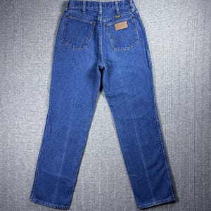 K&ouml;nnte beinhalten: Blaue Jeans aus Denim mit klassischem F&uuml;nf-Taschen-Design. Die Jeans haben einen geraden Beinverlauf und einen braunen Lederaufn&auml;her auf der Ges&auml;&szlig;tasche. Das Wrangler-Logo ist auf dem Aufn&auml;her sichtbar. Die Jeans bestehen aus strapazierf&auml;higem Denim-Stoff.