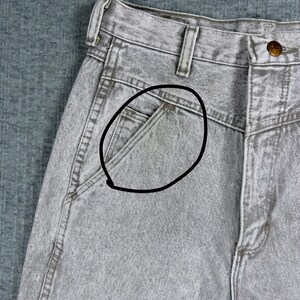 Peut inclure: Gros plan sur un jean en denim gris d&eacute;lav&eacute; &agrave; l'acide. Le jean a une conception classique &agrave; cinq poches, avec une petite poche sur le devant. Le denim a un aspect d&eacute;lav&eacute; et textur&eacute;. Le jean est boutonn&eacute; &agrave; la taille.