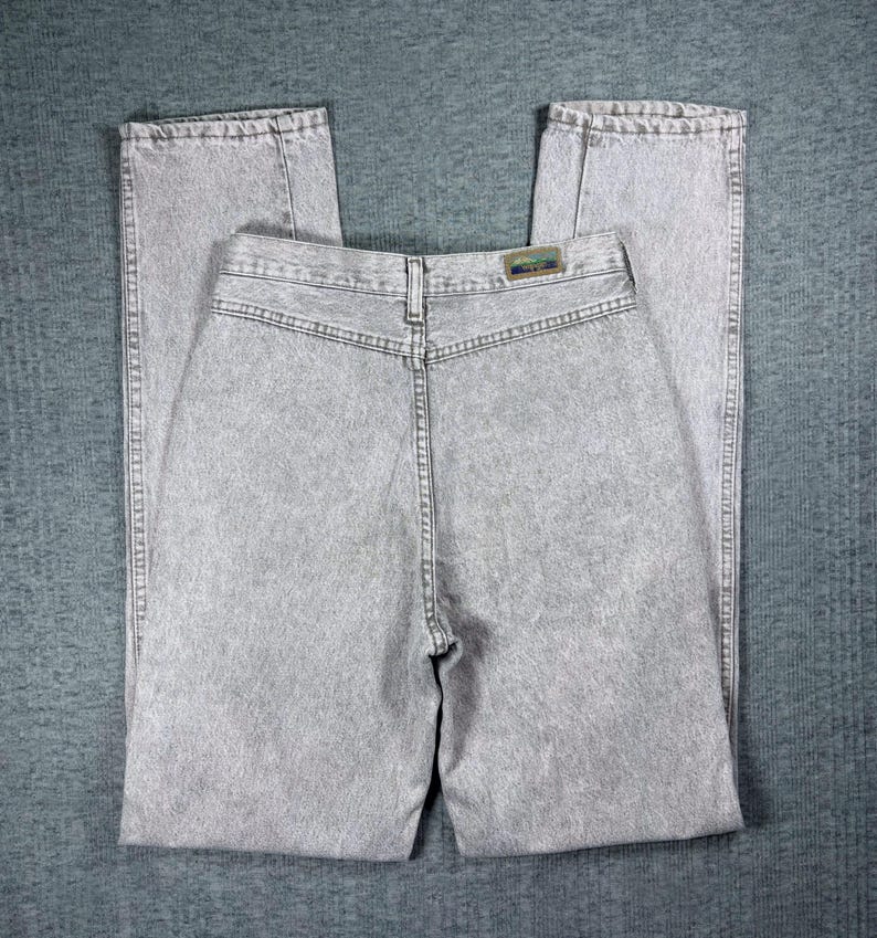Peut inclure: Jean clair d&eacute;lav&eacute; &agrave; l'acide. Le jean a une taille haute et une coupe droite. Le dos du jean est visible, montrant les poches, les passants de ceinture et une petite &eacute;tiquette. Le tissu a un aspect textur&eacute;.