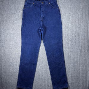 May include: Dark blue denim jeans with a classic five-pocket design. The jeans have a high waist and a straight leg cut. The denim is a solid, medium-weight fabric. The jeans are button and zipper closure.