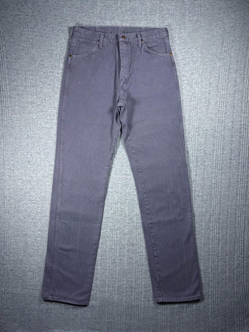 May include: A pair of gray denim jeans. The jeans have a classic five-pocket design, a button and zipper closure, and belt loops. The jeans are made of a durable denim fabric and have a straight leg fit.