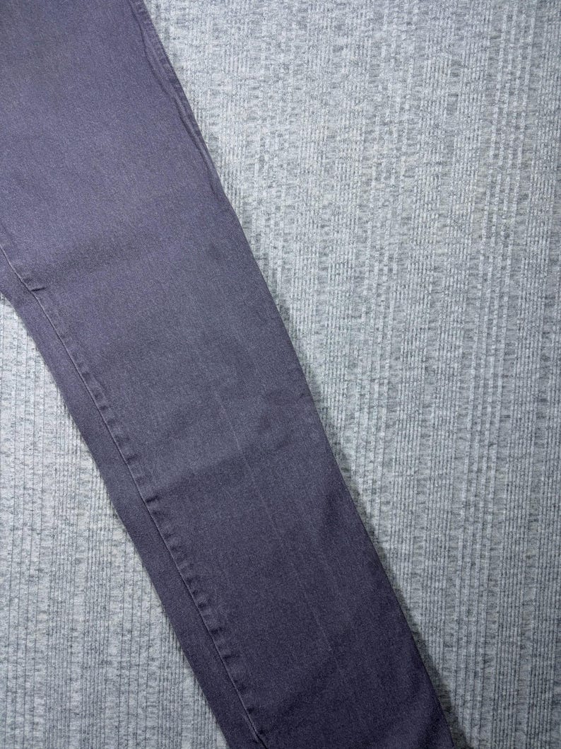 May include: A pair of dark gray denim jeans. The jeans are a solid color with visible seams and a classic five-pocket design. The fabric appears to be a medium weight denim.