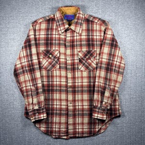 May include: A red, black, and cream plaid button-up shirt with two chest pockets. The shirt has a brown corduroy collar and buttoned cuffs. The shirt is made of a thick, warm material.