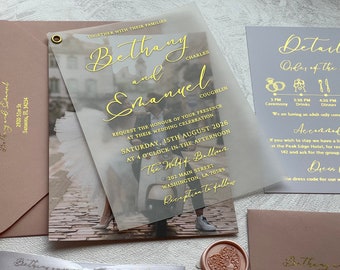 May include: A wedding invitation with a translucent overlay featuring a photo of a couple on a scooter. The invitation is printed with gold lettering and includes the names Bethany and Emanuel, the date Saturday, 15th August 2026, and the time 4 o'clock in the afternoon. The invitation also includes the location The Wolff Ballroom, 202 Main Street, Washington, LA 70589. The invitation is accompanied by a smaller card with details about the wedding ceremony and reception.
