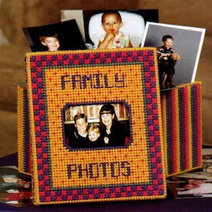 May include: A rectangular plastic canvas photo storage box featuring a yellow center panel with the purple stitched text FAMILY PHOTOS and a central window displaying a photograph of three people. The box has a purple and red checkered border.