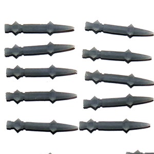 May include: A collection of gray plastic model missiles arranged on a white background. Each missile has a pointed tip and a decorative midsection. The missiles are evenly spaced, suggesting a set or collection.