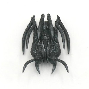 May include: A dark gray, insect-like sculpture with multiple claw-like appendages. The detailed, textured surface suggests a creature or alien design, possibly for a fantasy or sci-fi setting. The object is centered against a white background.