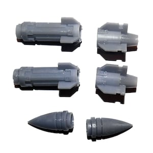 May include: Six gray plastic model rocket parts are arranged on a white surface. The parts include cylindrical bodies with fins and a conical nose cone. The components are designed for model building or crafting projects.