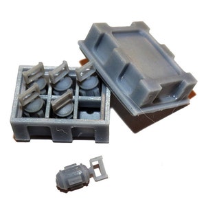 May include: A collection of small, gray plastic model parts, including cylindrical components with rectangular handles and a small crate. The crate is open, revealing several of the components. The lid is also visible.