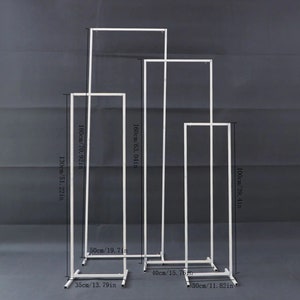 May include: White metal wedding arch set. The tallest arch is 180cm (70.92 in) tall, and the shortest is 100cm (39.4 in) tall. The arches are rectangular and stand on square bases. The set includes four arches of varying heights and widths.