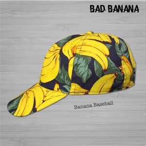 Pu&ograve; includere: Un cappello da baseball nero con una stampa di banane gialle. Il cappello ha una visiera curva e una parte posteriore in rete. Il testo "BAD BANANA" &egrave; stampato in bianco sulla parte anteriore del cappello. Il testo "Banana Baseball" &egrave; stampato in bianco sulla parte posteriore del cappello.