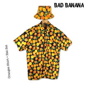 May include: A black button-up shirt with a short sleeve and an all-over orange print. The shirt has a pocket on the left side. A matching orange bucket hat with green leaves is included. The text "BAD BANANA" is printed in white on a black background. The text "Oranges Shirt + Hat Set" is printed on the left side of the image.