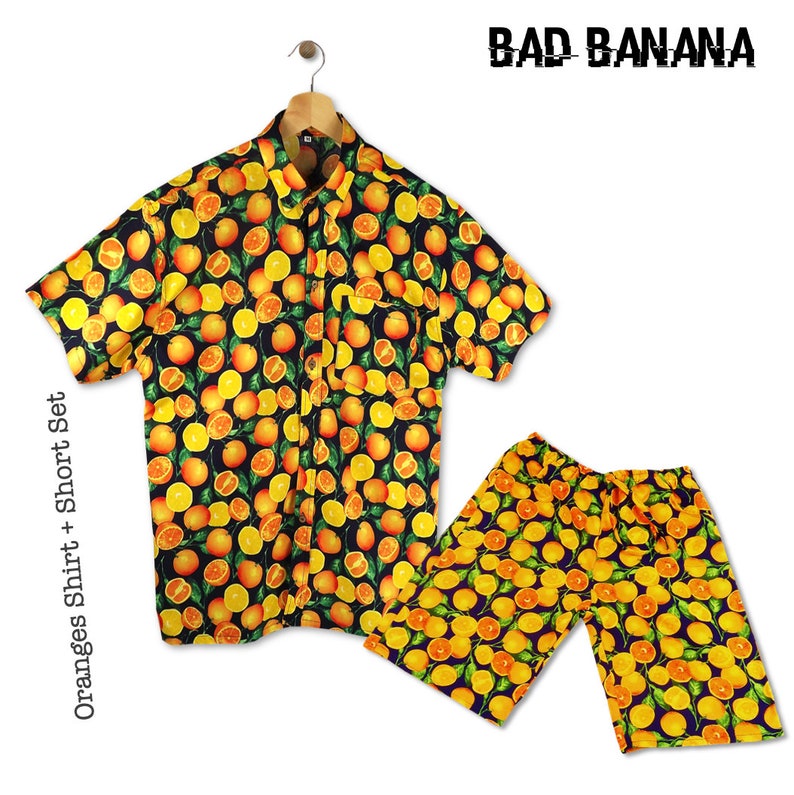 May include: A black and orange short-sleeved button-up shirt and matching shorts with a repeating pattern of oranges and leaves. The text "BAD BANANA" is printed in white on a black background above the shirt. The text "Oranges Shirt + Short Set" is printed vertically on the left side of the image.