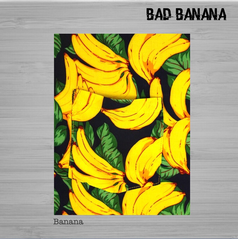 Pu&ograve; includere: Un tessuto nero con un motivo ripetuto di banane gialle e foglie verdi. Il testo "BAD BANANA" &egrave; stampato in bianco nella parte superiore del tessuto. Il testo "Banana." &egrave; stampato in bianco nella parte inferiore del tessuto.