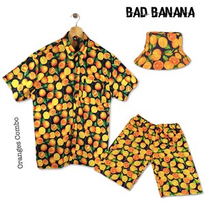 May include: A black, short-sleeved button-down shirt with a yellow and orange orange slice print. Matching yellow and orange shorts and a black bucket hat with the same print. The text "BAD BANANA" is printed in white on the hat. The text "Oranges Combo" is printed vertically on the left side of the image.