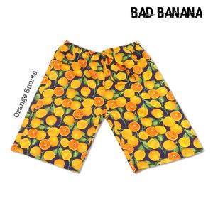 May include: Orange shorts with a navy blue background and a repeating pattern of yellow oranges with green leaves. The text "BAD BANANA" is printed in white at the top of the image.