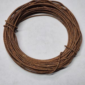 May include: A coil of rusty brown wire. The wire is coiled into a circle and is about 10 inches in diameter.