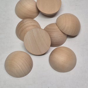 May include: Eight unfinished wooden half spheres. The spheres are light brown and have a smooth, slightly textured surface.