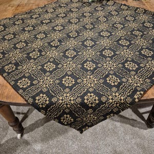 May include: Black and gold woven table runner with a geometric pattern. The runner is on a wooden table.