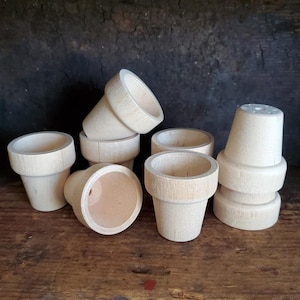 May include: A set of eight unfinished wooden plant pots in various sizes. The pots are made of natural wood and have a smooth, unpainted surface.