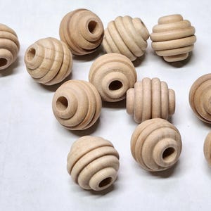 May include: A group of 12 natural wood beads with a grooved design. The beads are round and have a hole in the center for stringing.
