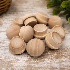 May include: A collection of small, unfinished wooden plugs with a rounded top and a cylindrical base. These light-colored, natural wood components feature a smooth, sanded texture and are shaped like miniature mushrooms, designed for various craft projects.