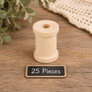 May include: A light-colored, cylindrical wooden spool with a central hole, positioned above a small, rectangular black sign with a wooden border that features the white printed text 25 Pieces, indicating a set of twenty-five individual items.