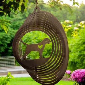 May include: A metal wind chime featuring a silhouette of a dog with a heart on its chest. The chime is suspended from a tree branch and has a circular design with multiple layers.