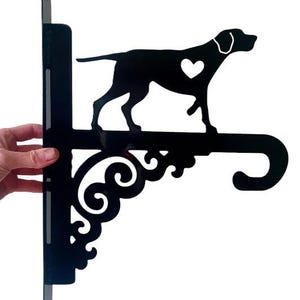 May include: Black metal bracket with a decorative scroll design. A silhouette of a dog with a heart on its chest is attached to the bracket.