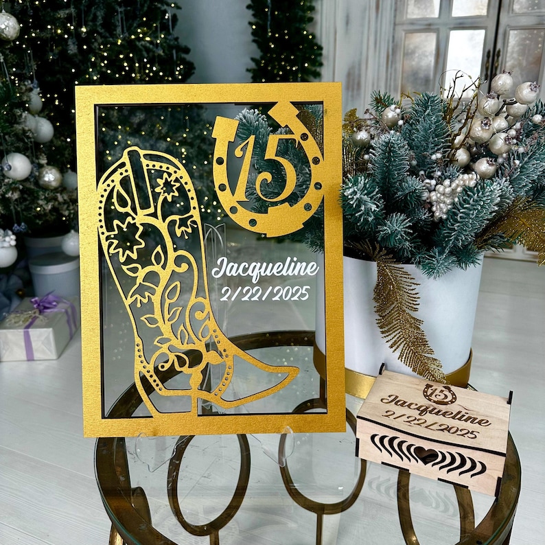 May include: Gold-colored frame with a cutout of a cowboy boot and horseshoe with the number 15 inside. The frame has the name Jacqueline and the date 2/22/2025. A small wooden box with the same design and text is in the foreground.