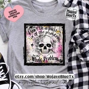 Op de afbeelding: Een grijs T-shirt met een zwart-witte afbeelding van een schedel met bloemen en de tekst "Wees geen deel van het probleem, wees het hele probleem".