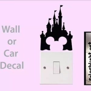 May include: Black silhouette of a castle with Mickey Mouse ears, designed as a wall or car decal. The decal is placed above a white light switch. Text on the left reads "Wall or Car Decal". The right side has the text "splashlight-art".
