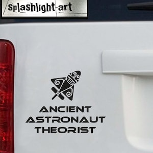 May include: Black decal featuring a stylized spaceship design with the text "ANCIENT ASTRONAUT THEORIST." The decal also includes the text "splashlight-art" in a rectangular box. The design is suitable for vehicles or other surfaces.
